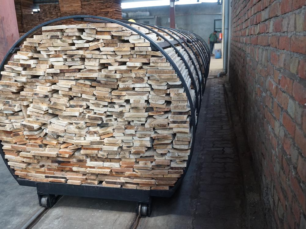 A cylindrical charge of sawn timber loaded on a bogie beside the treatment vessel