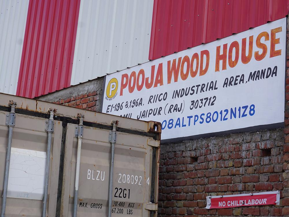 Container being loaded beside the Pooja Wood House signboard at Manda