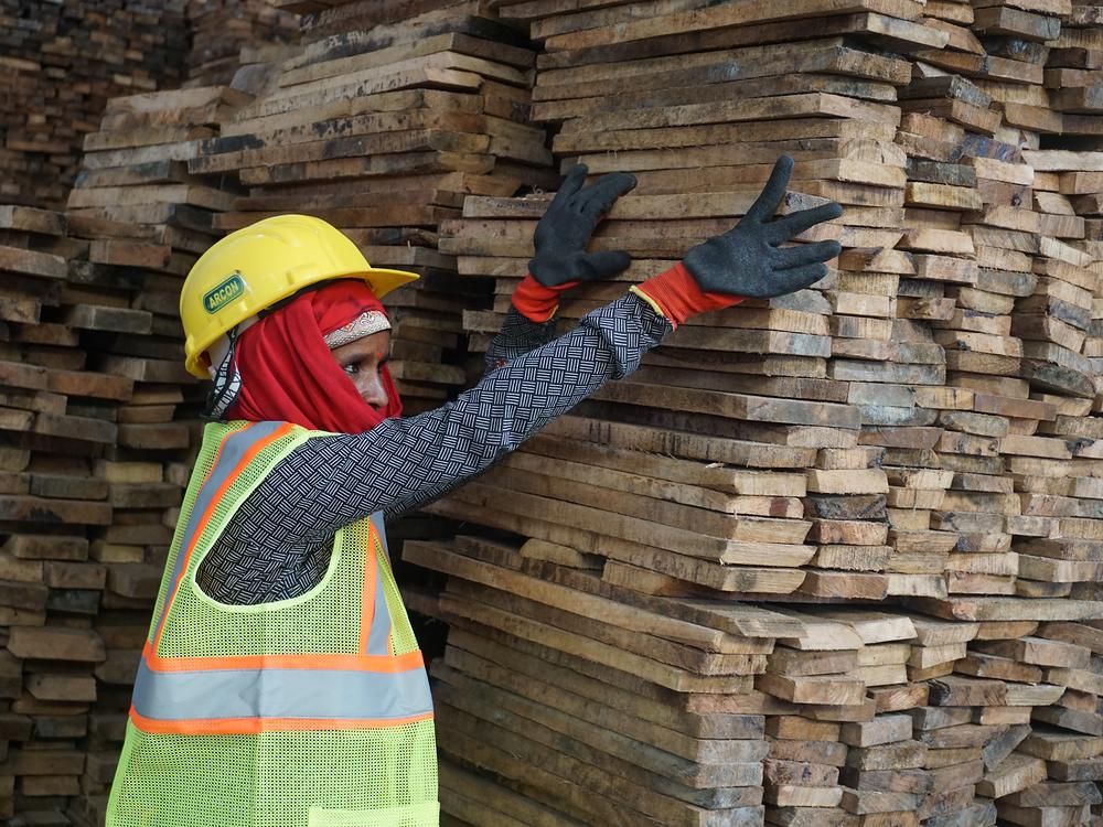 A team member in protective equipment checking boards on a stack