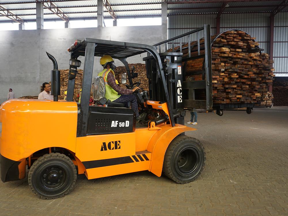 Forklift moving stacked timber inside a covered store