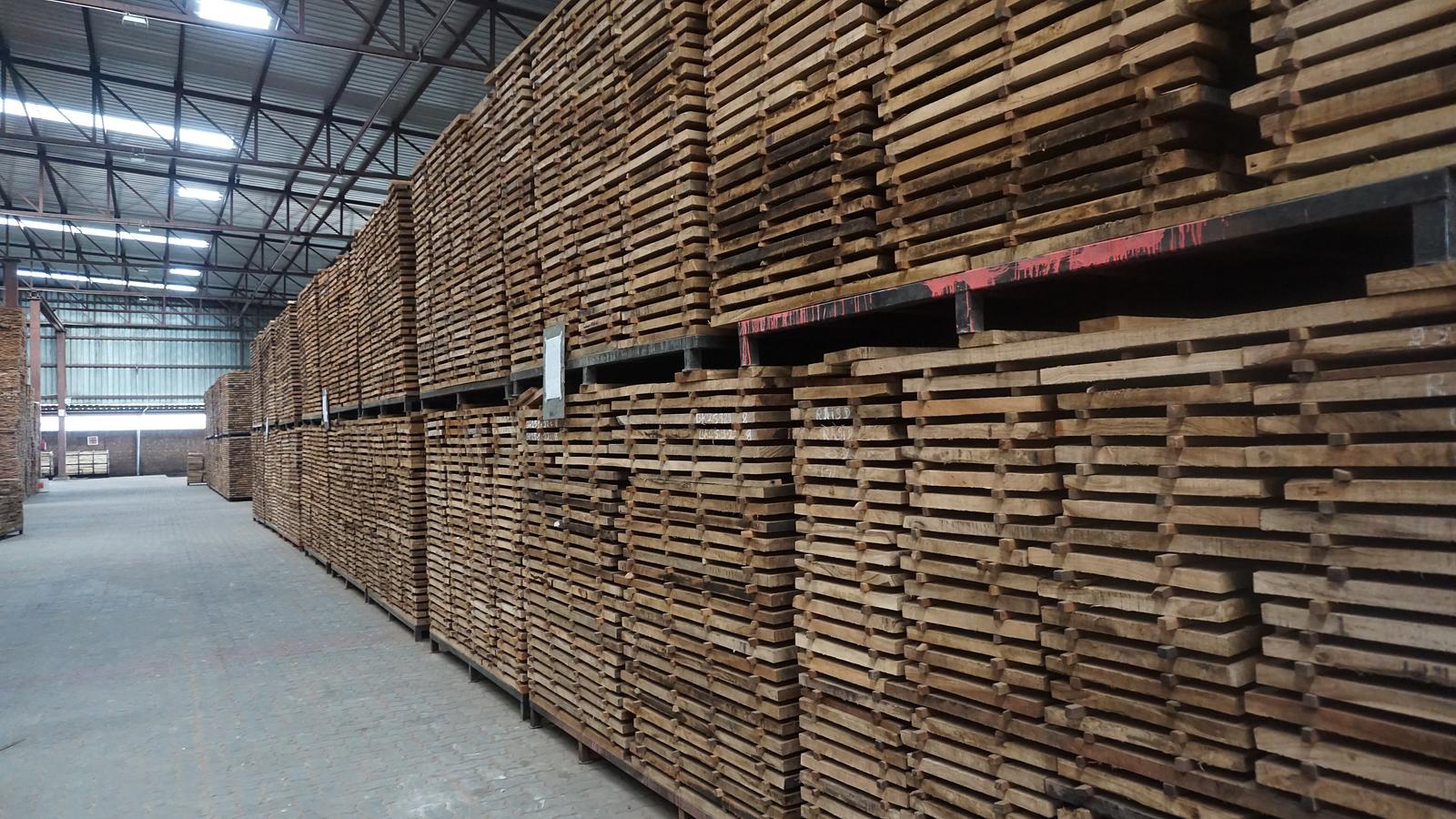 Aisle between tall stacks of graded sawn boards inside a covered timber store