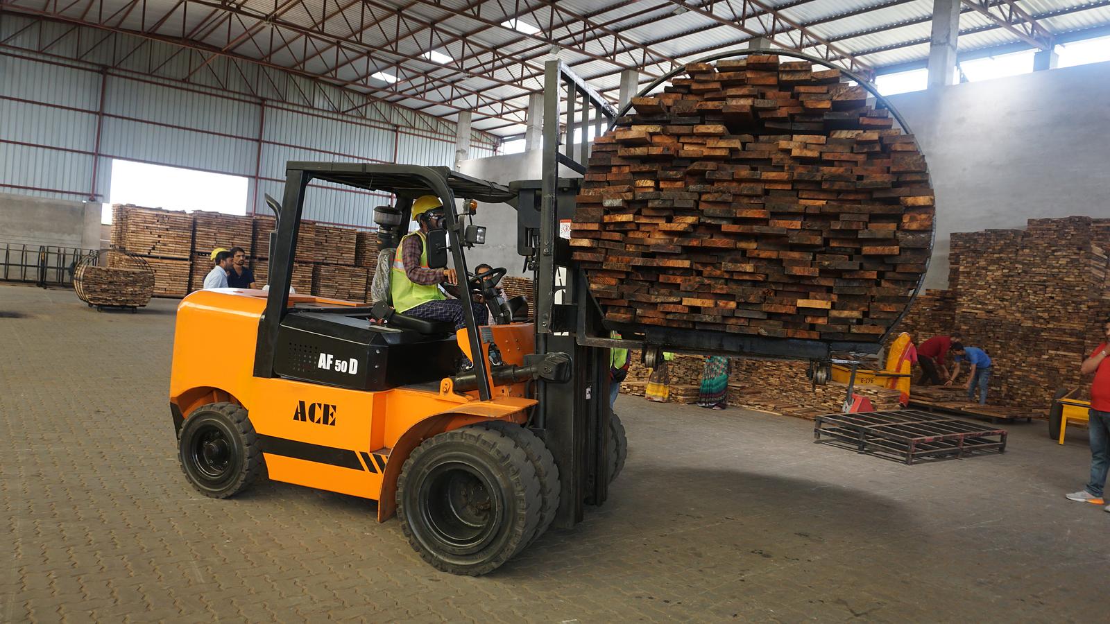 Forklift moving stacked timber inside a covered store